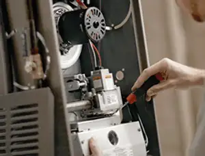 Furnace repair technician inspecting internal components and wiring in Ogden, UT