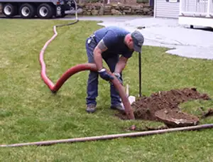 Septic pumping technician servicing a residential septic tank with a vacuum hose in Ogden, UT