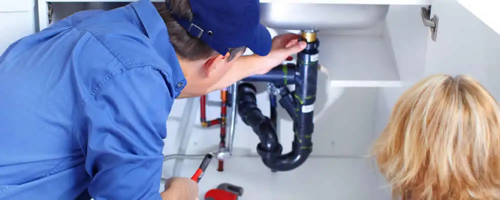 Plumber repairing under-sink drain pipes and fittings in Ogden, UT